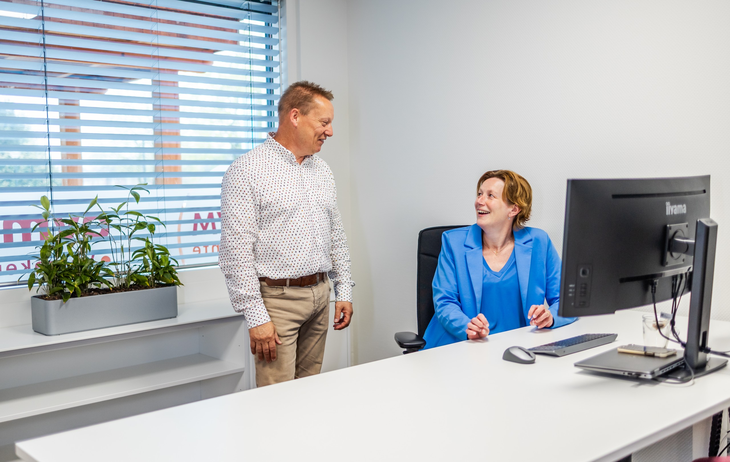 Directie team OVM Twente. 1 persoon zit aan bureau achter computer en 1 persoon staat naast de zittende persoon.